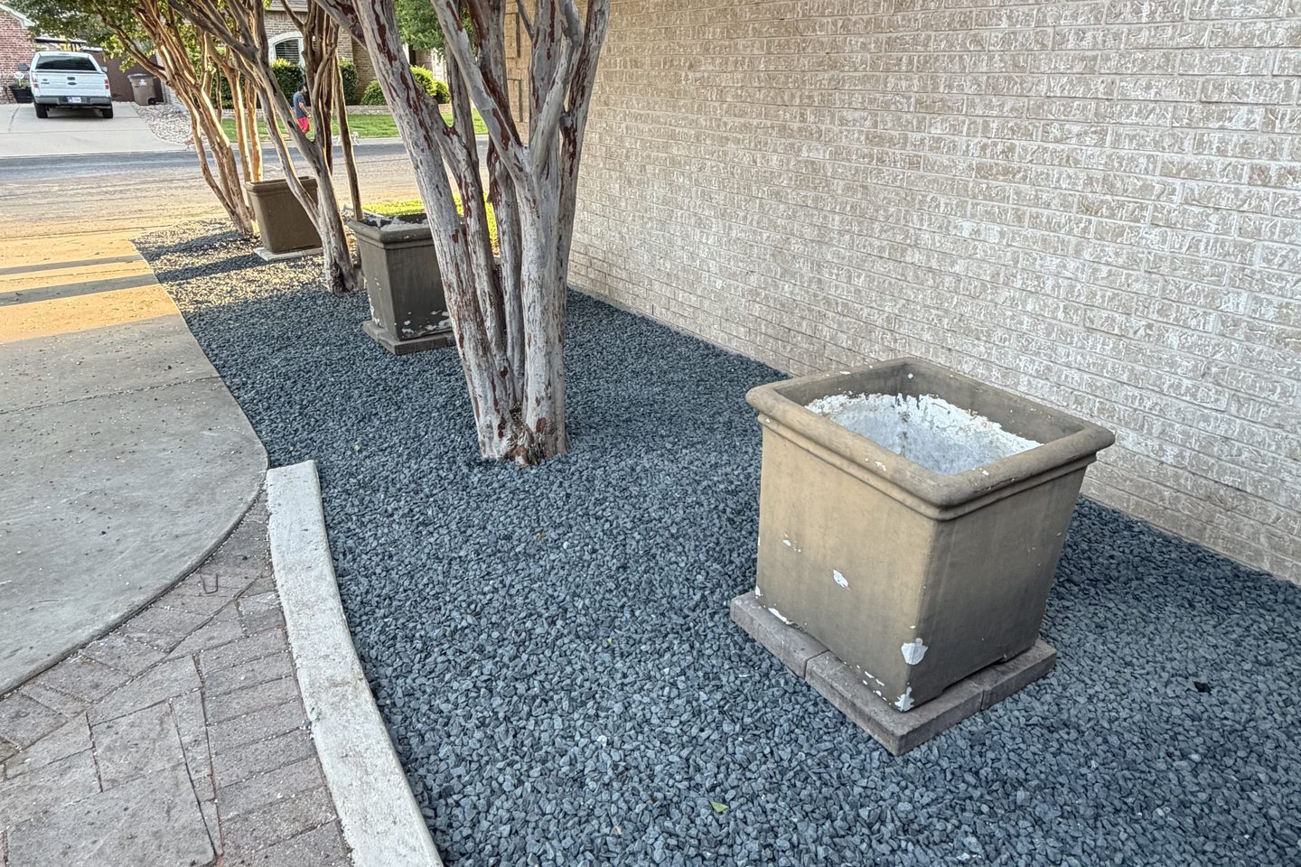 After: the same crape myrtle bed finished in dark gravel