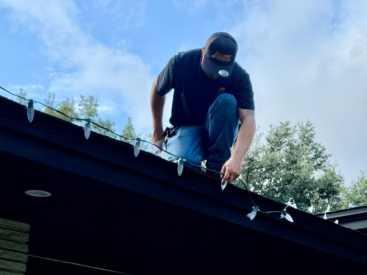 Ascend crew member on a roof installing Christmas lights along the roofline