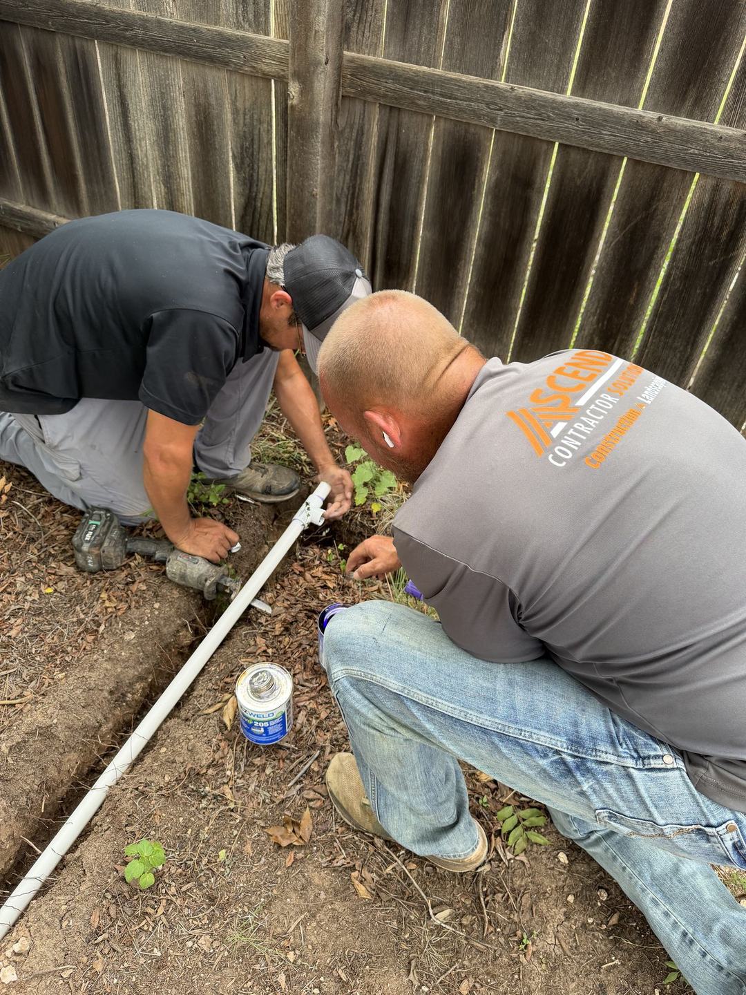Crew installing irrigation pipe along a fence line