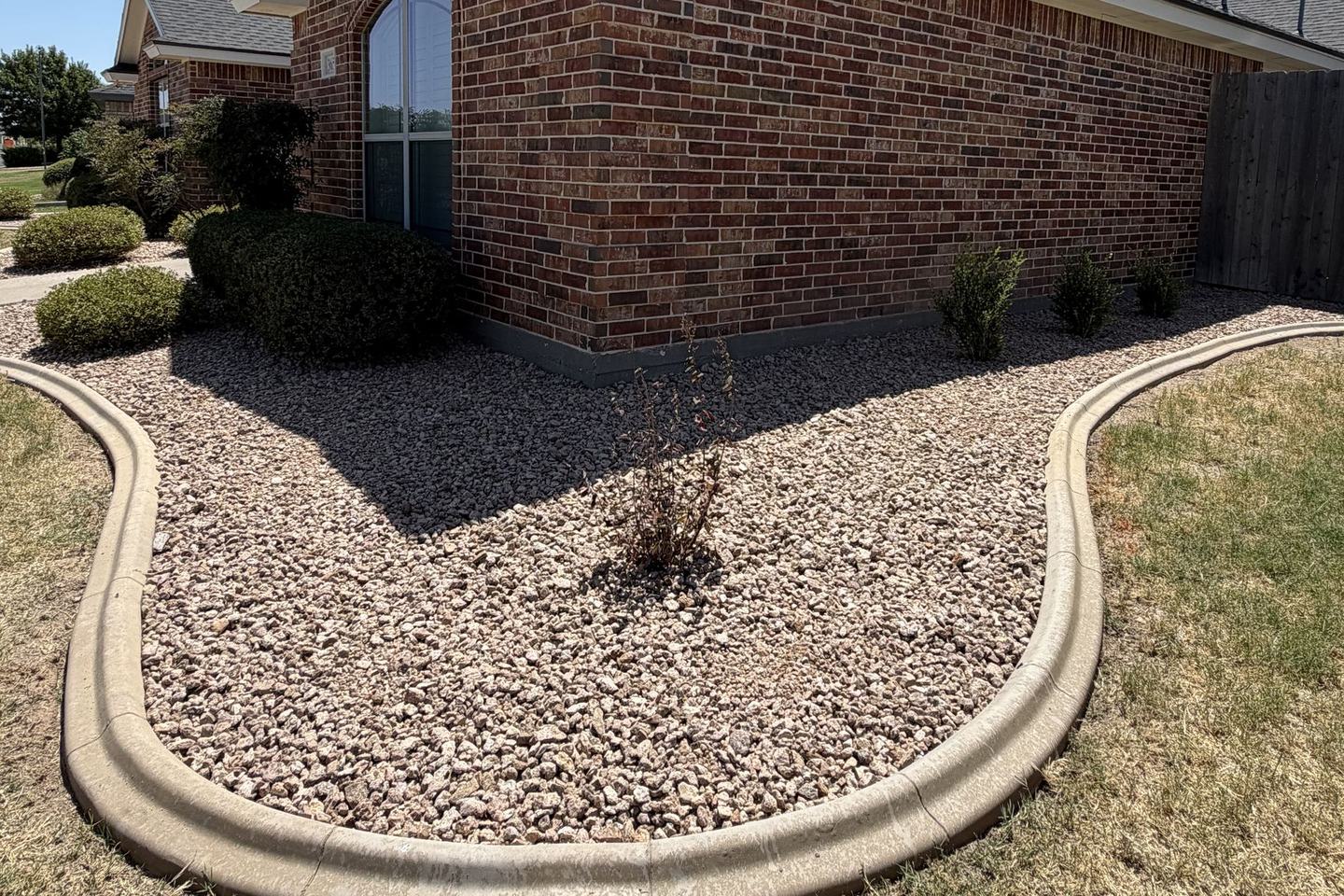 After: rock bed with concrete curbing beside the same home