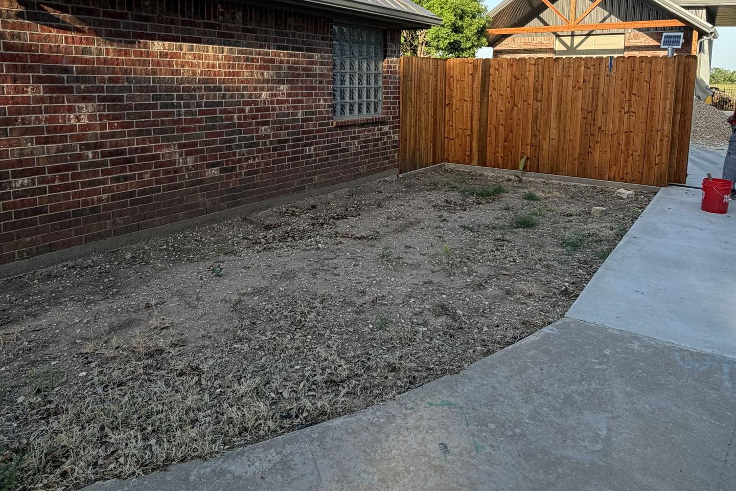 Before: bare dirt side yard beside a brick home